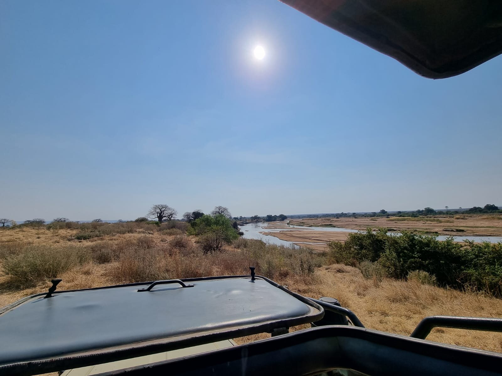 Sandy river and baobabs seen from the roof of a vehicle