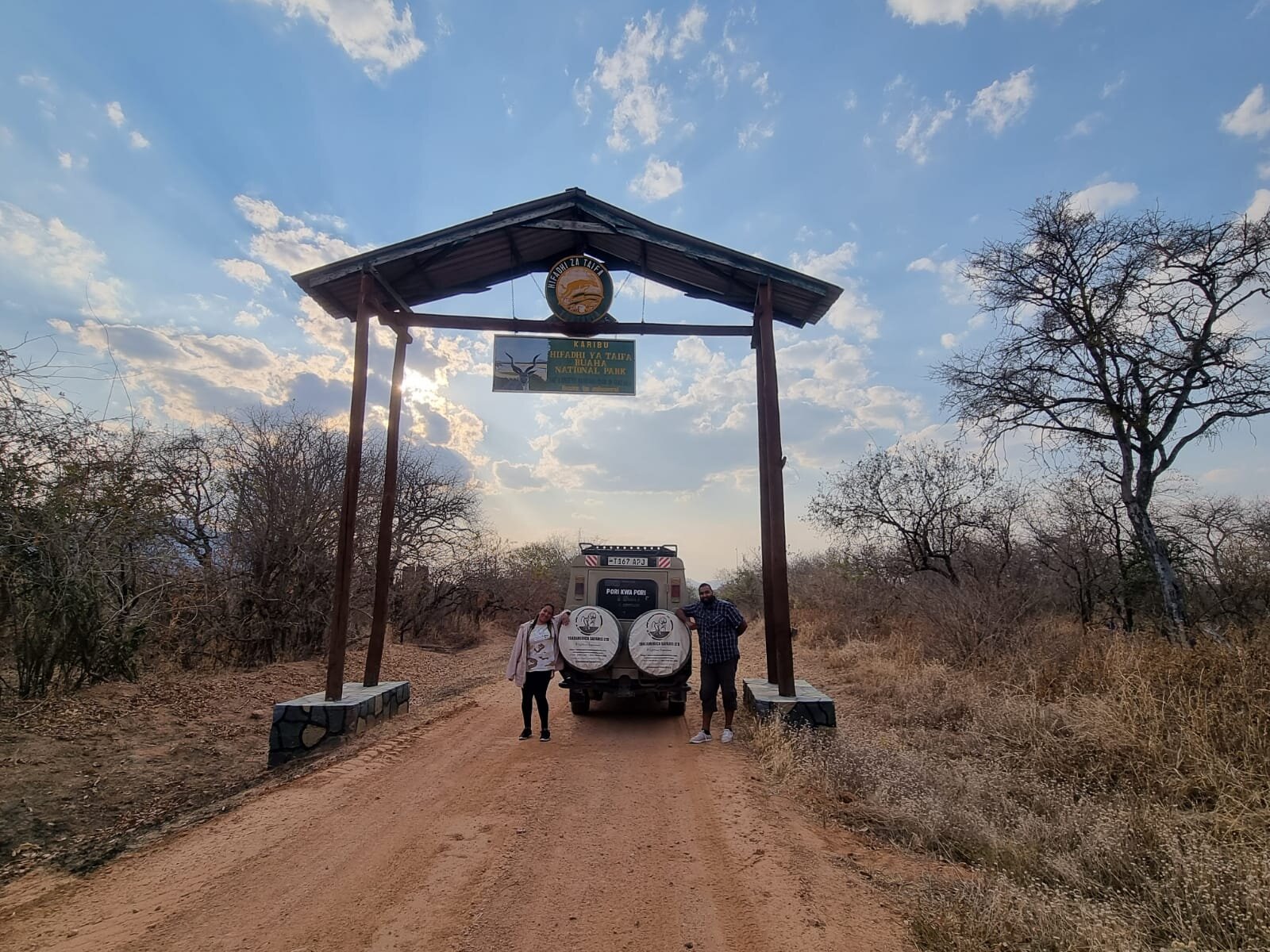 Two visitors standing at the entrance gate of Ruaha National Park